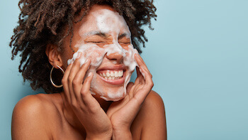 Dark skinned woman enjoys skincare product