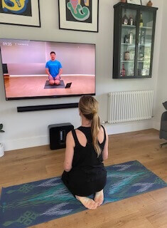 Woman doing yoga in Bam Clothing yoga wear in front of TV